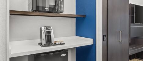 Una kitchenette equipada con microondas, cafetera y un refrigerador pequeño.