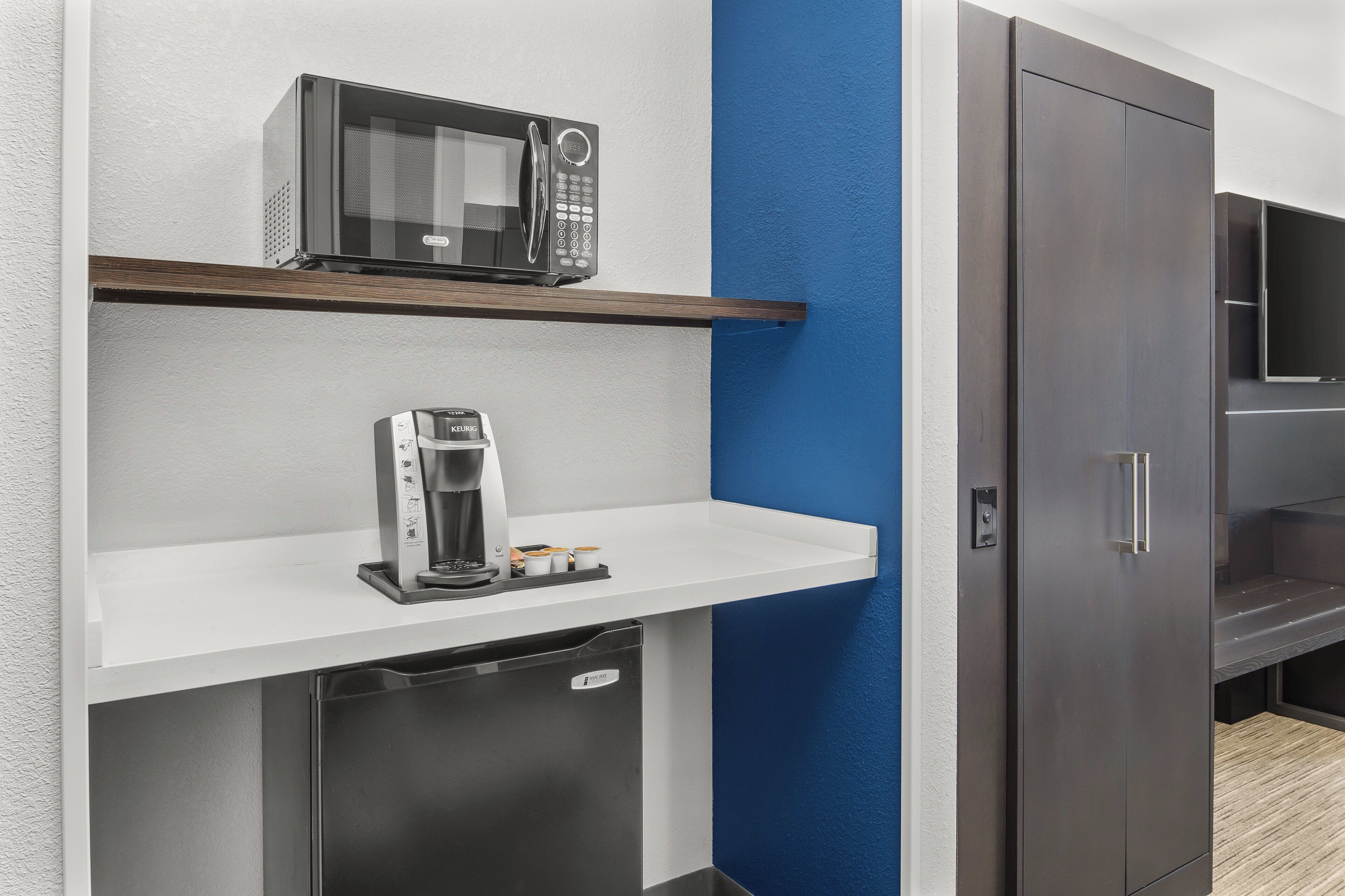 A kitchenette with a microwave, coffee maker, and a small refrigerator.