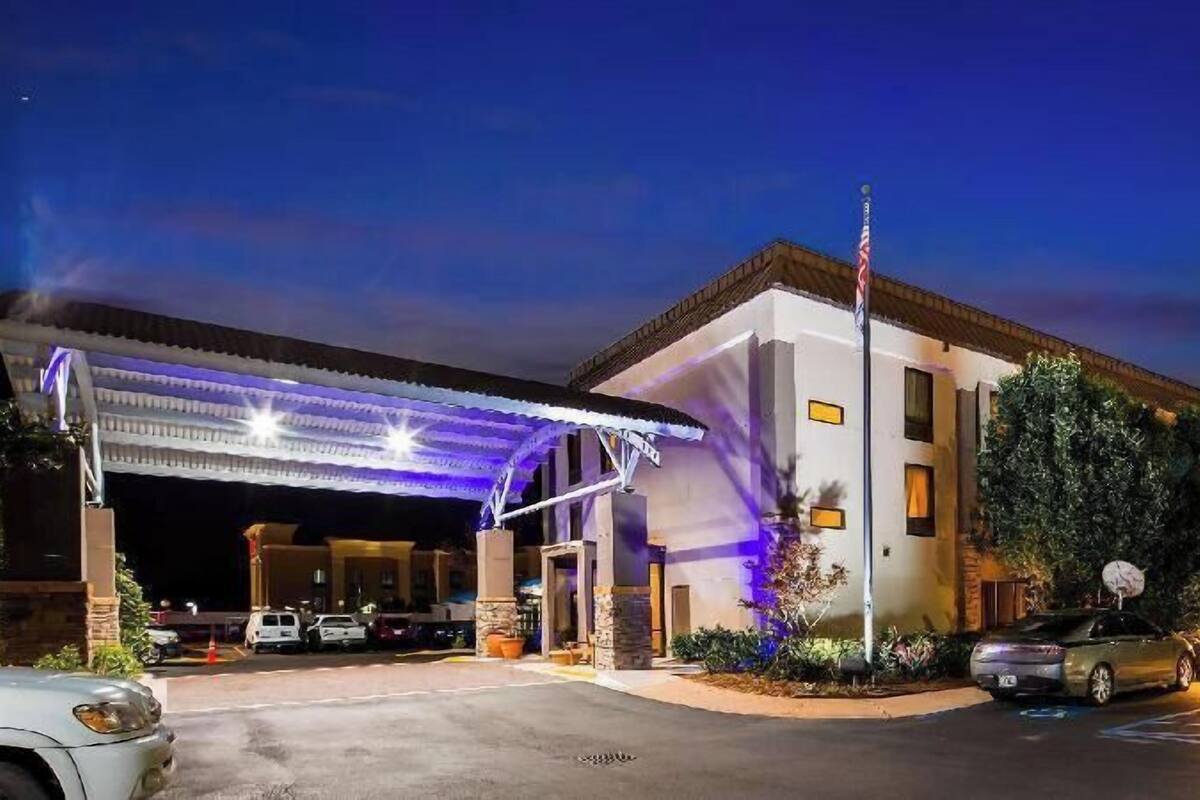 A hotel with a covered entrance, a flagpole, and a parking lot.