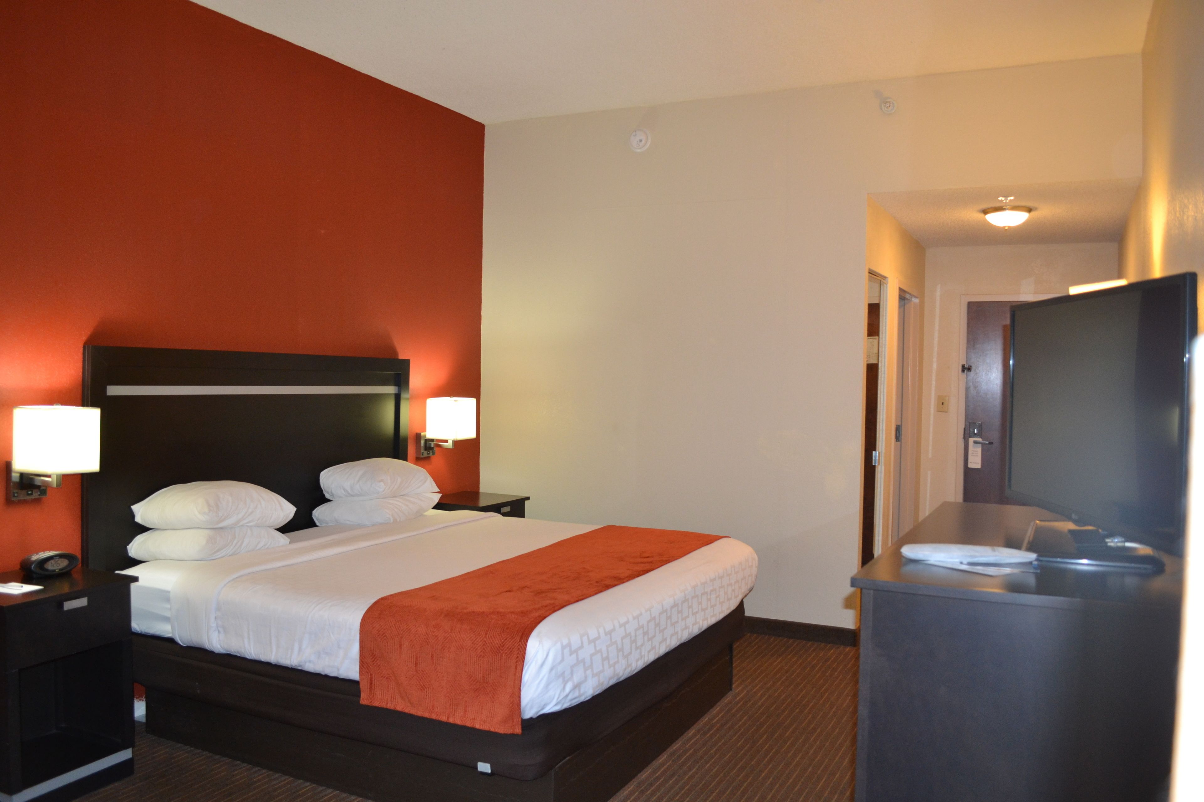 Hotelkamer met een groot bed, twee nachtkastjes met lampen, een flatscreen televisie en een bureau met stoel.