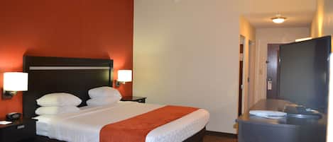 A hotel room with a large bed, two bedside tables with lamps, a flat-screen TV, and a desk with a chair.