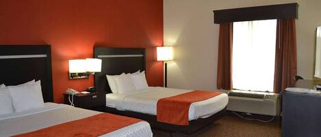 Habitación de hotel con dos camas, un escritorio, teléfono, lámpara, aire acondicionado y ventana con cortinas.