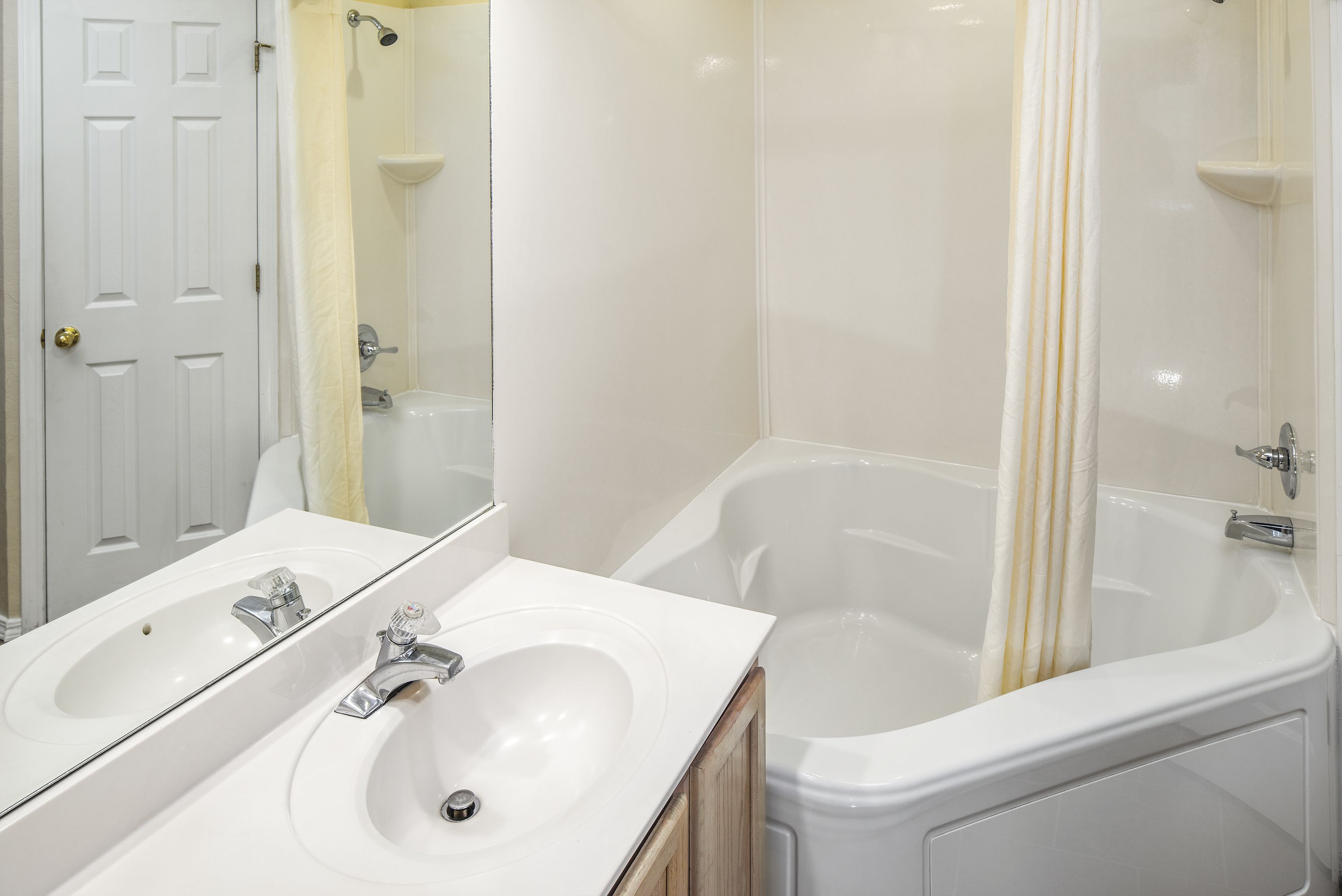 A bathroom with a double sink, a bathtub, and a shower.