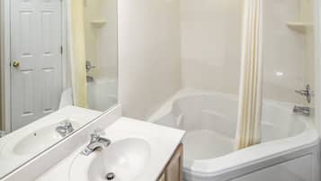 A bathroom with a double sink, a bathtub, and a shower.