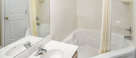 A bathroom with a double sink, a bathtub, and a shower.