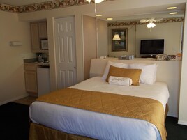 Una habitación de hotel con cama, escritorio, televisor y baño.
