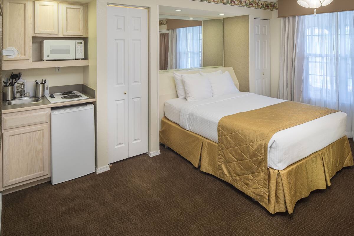 Una habitación de hotel con cama, microondas, mini refrigerador y pequeña kitchenette.
