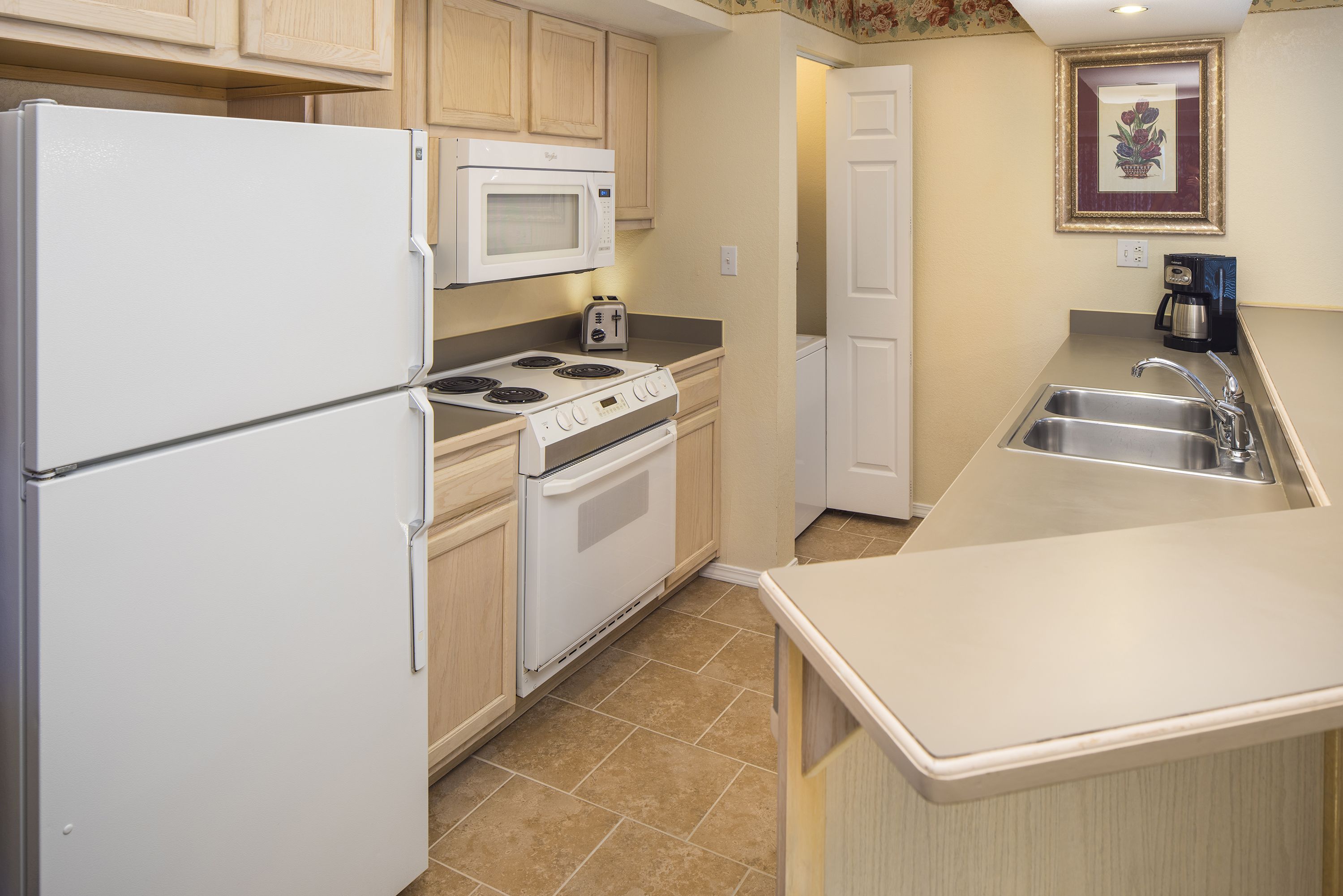 A compact kitchen with a refrigerator, microwave, stove, and sink.