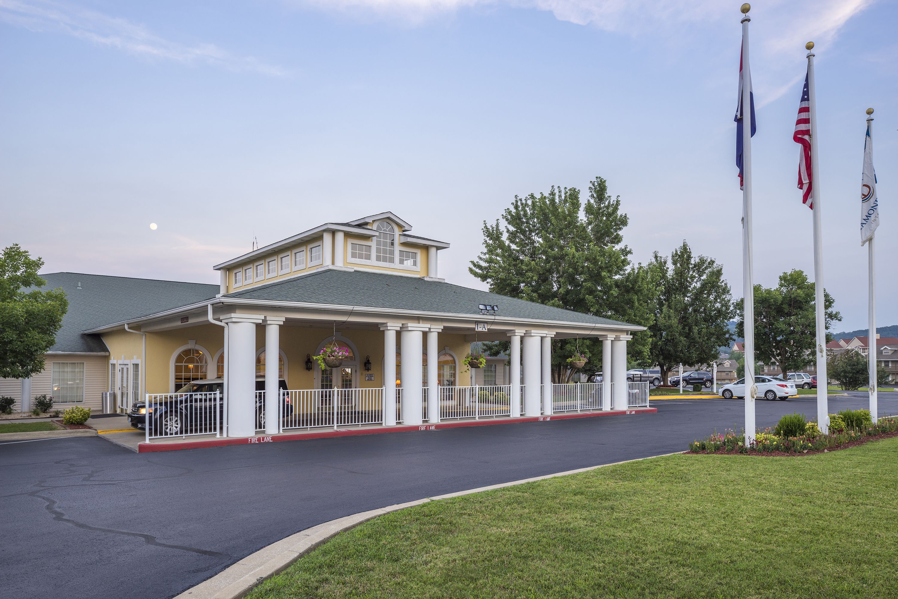 A building with a covered entrance, columns, and flags.