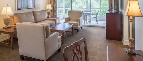 A living room with a sofa, chairs, a table, and a TV.