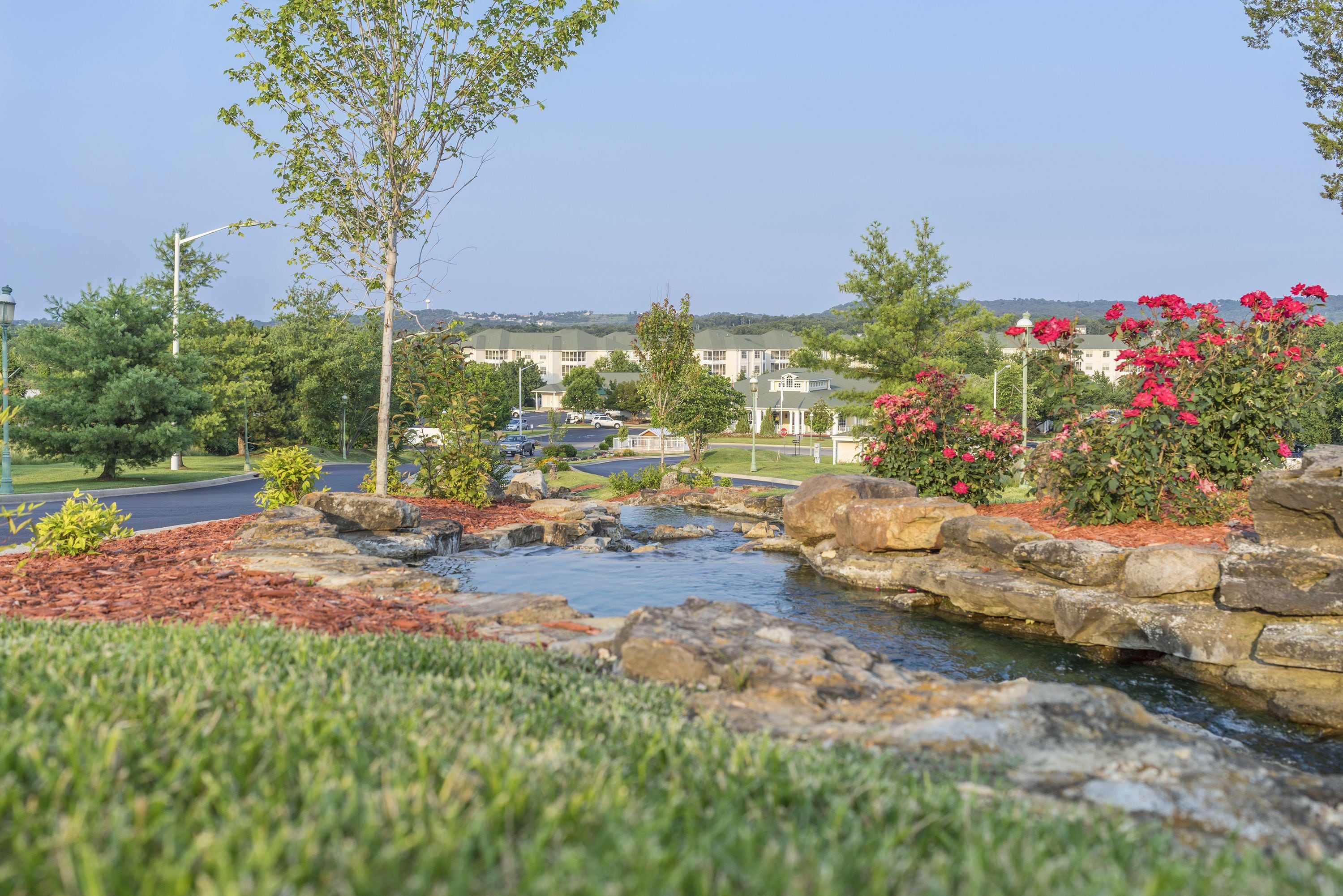 A landscaped area with a small water feature, stone walls, and flowering plants.