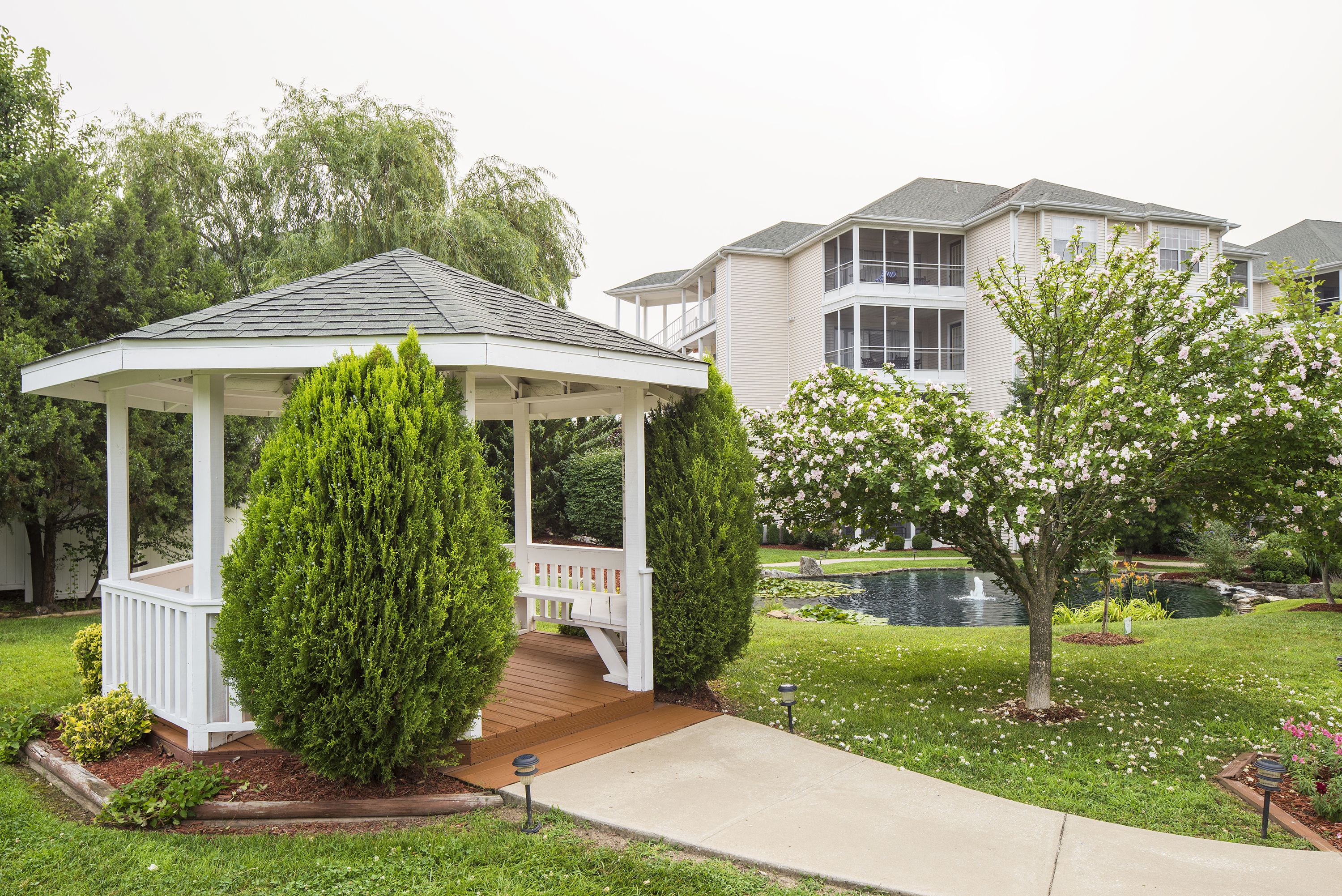 Ein Pavillon mit einer Holterrasse, umgeben von gepflegtem Rasen und einem Teich.
