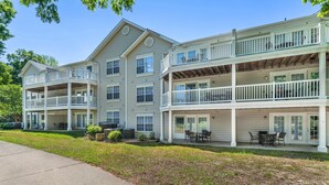 A multi-story residential building with balconies, outdoor seating, and a well-maintained lawn.