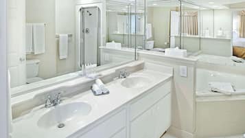 Un baño moderno con dos lavamanos, una cabina de ducha de vidrio y un espejo grande.