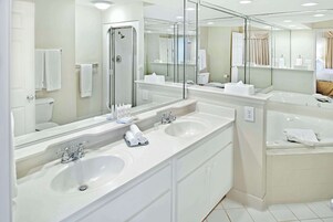 Un baño moderno con dos lavamanos, una cabina de ducha de vidrio y un espejo grande.