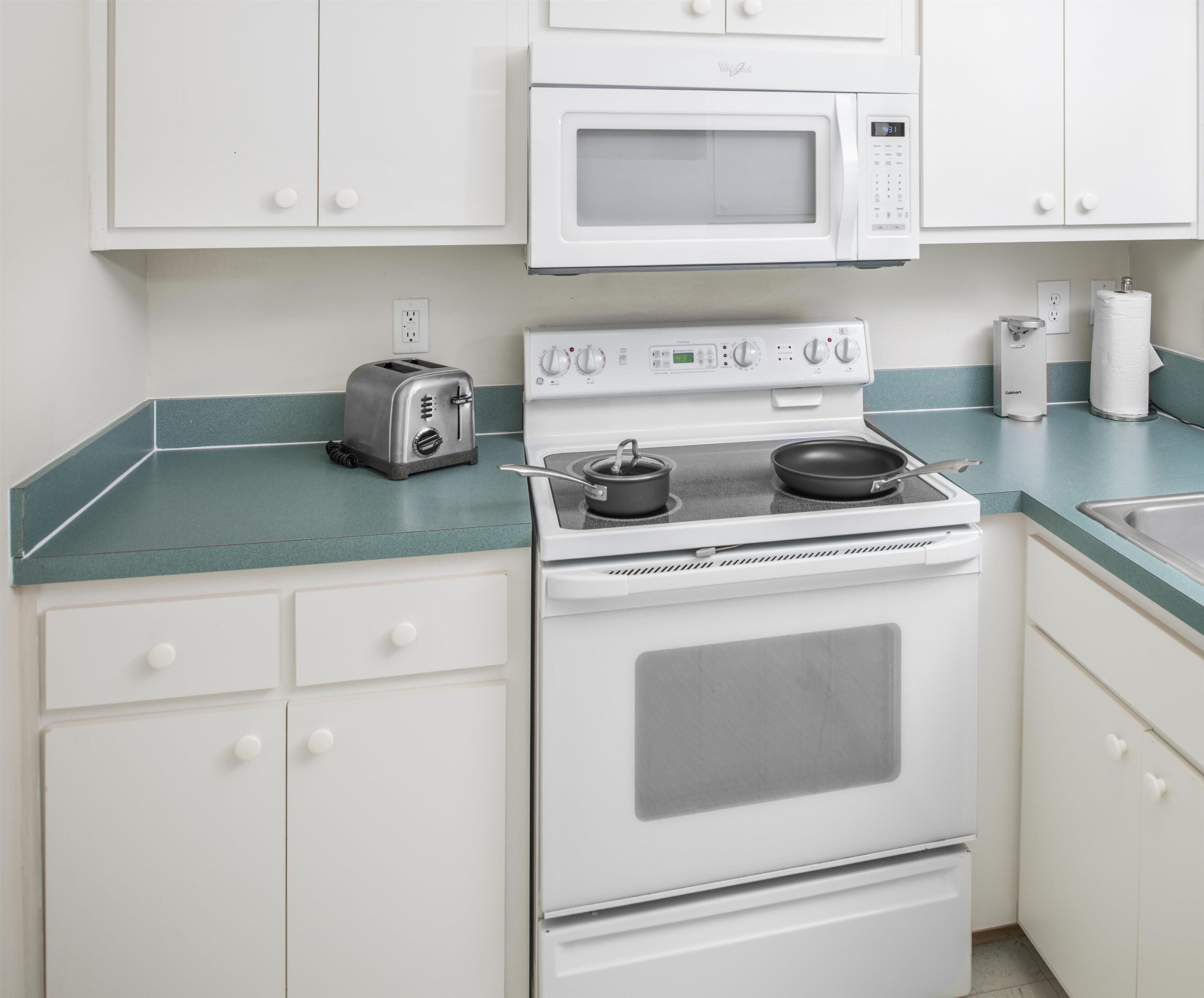 A kitchen with a white stove, a microwave, a toaster, and a sink.