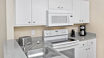 A kitchenette with a microwave, toaster, stove, sink, and cabinets.