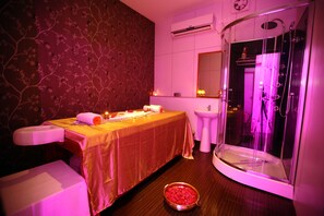 A room with a massage table, a shower enclosure, a sink, and a decorative wall. - Raj Park Chennai (Chennai)