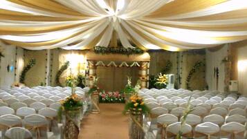 A church interior with rows of white chairs, a central aisle, and floral decorations.