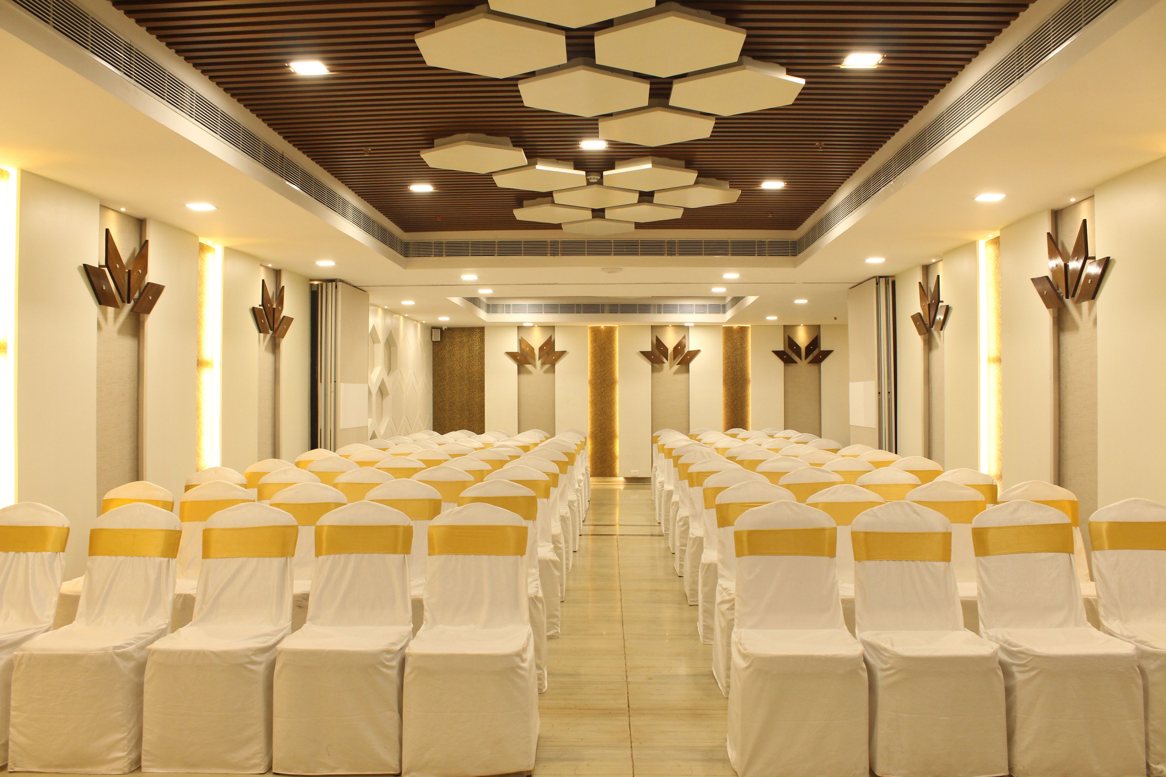 A conference room with rows of chairs, a wooden ceiling, and wall-mounted light fixtures.