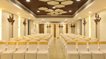 A conference room with rows of chairs, a wooden ceiling, and wall-mounted light fixtures.