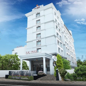 Een meerlaags hotel genaamd Raj Park, met een opvallende ingang en een aangelegde tuin.