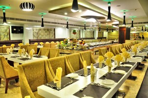 Un restaurante de servicio bufé con varias mesas largas, cada una dispuesta con platos blancos, cubiertos y servilletas amarillas.