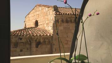 Vista de un edificio de piedra con tejado de tejas y una pequeña ventana de arco.
