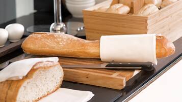 A kitchen counter with a loaf of bread, a knife, and a cutting board.