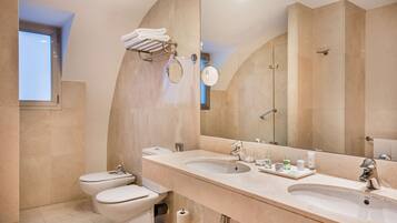 A modern bathroom with two toilets, a large sink, and a mirror.
