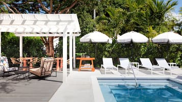 Een buitenzwembad, ligstoelen bij het zwembad