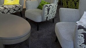 A modern lobby with grey upholstered chairs, a reception desk, and a round table. - marc münchen - Adults Only (Munich)