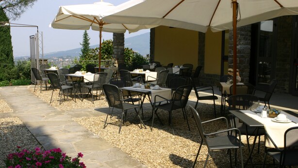 Een buitenruimte met eettafels, stoelen, parasols en een pad van stenen.
