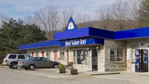 A building with a blue roof and a sign that reads "First Water Inn." There are cars parked in front and a small outdoor seating area.