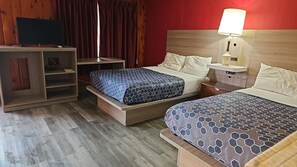 Quarto de hotel com duas camas, uma mesa, televisão e uma luminária.