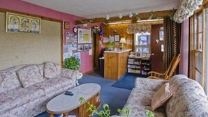 Ein gemütliches Wohnzimmer mit einer Couch, einem Couchtisch und einer kleinen Küchenzeile mit Arbeitsfläche und Schränken.