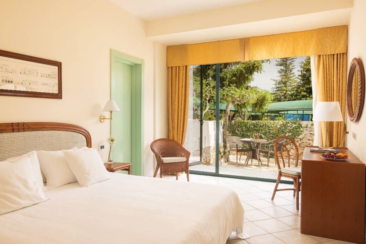 Une chambre d’hôtel avec un grand lit, une table à manger, des chaises et un balcon donnant sur l’extérieur.