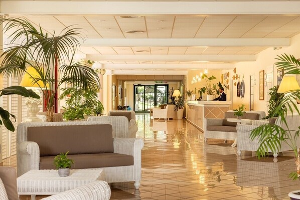 A spacious lobby with a reception desk, comfortable seating, and potted plants. - Hotel Sierra Silvana (Fasano)