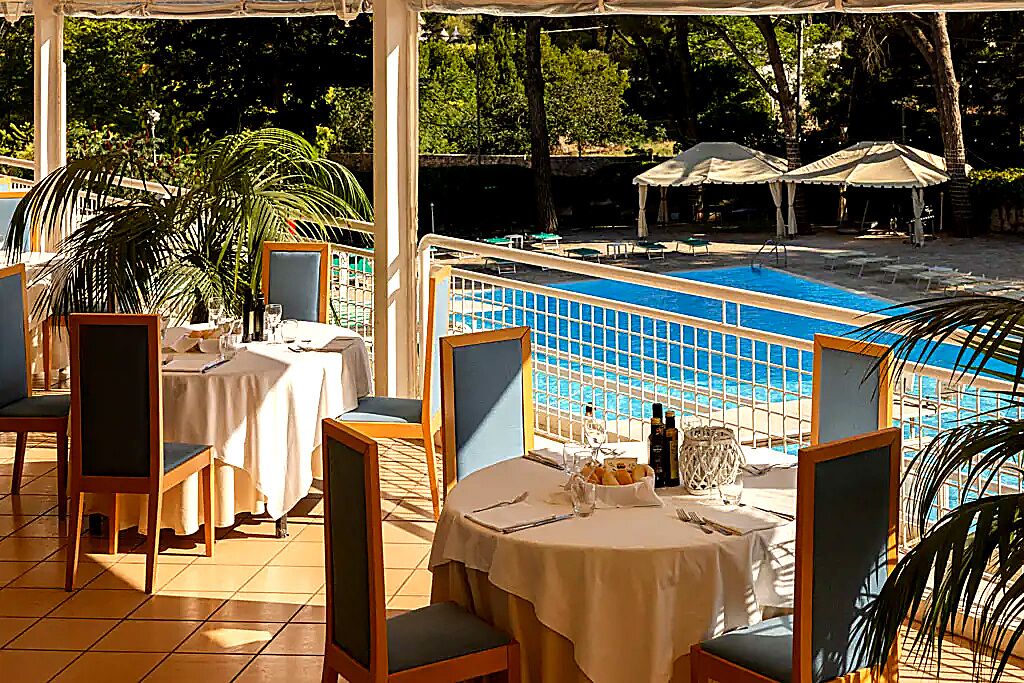 Ein Poolrestaurant mit Tischen, Stühlen und Sonnenschirmen.