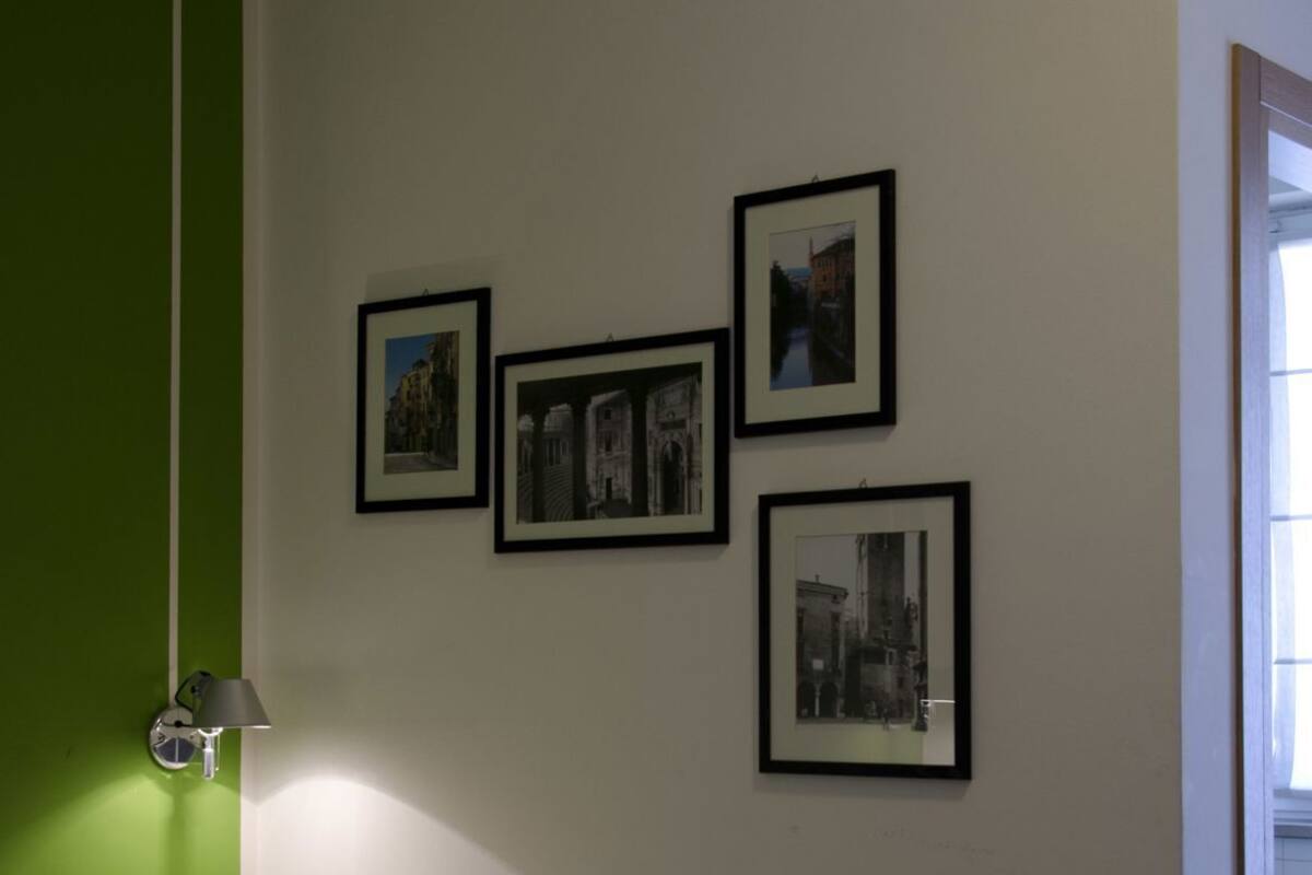 Una stanza con un letto, una parete verde decorativa e quattro quadri appesi al muro.