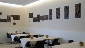 A conference room with tables, chairs, and artwork on the walls. - Hotel Key (Vicenza)