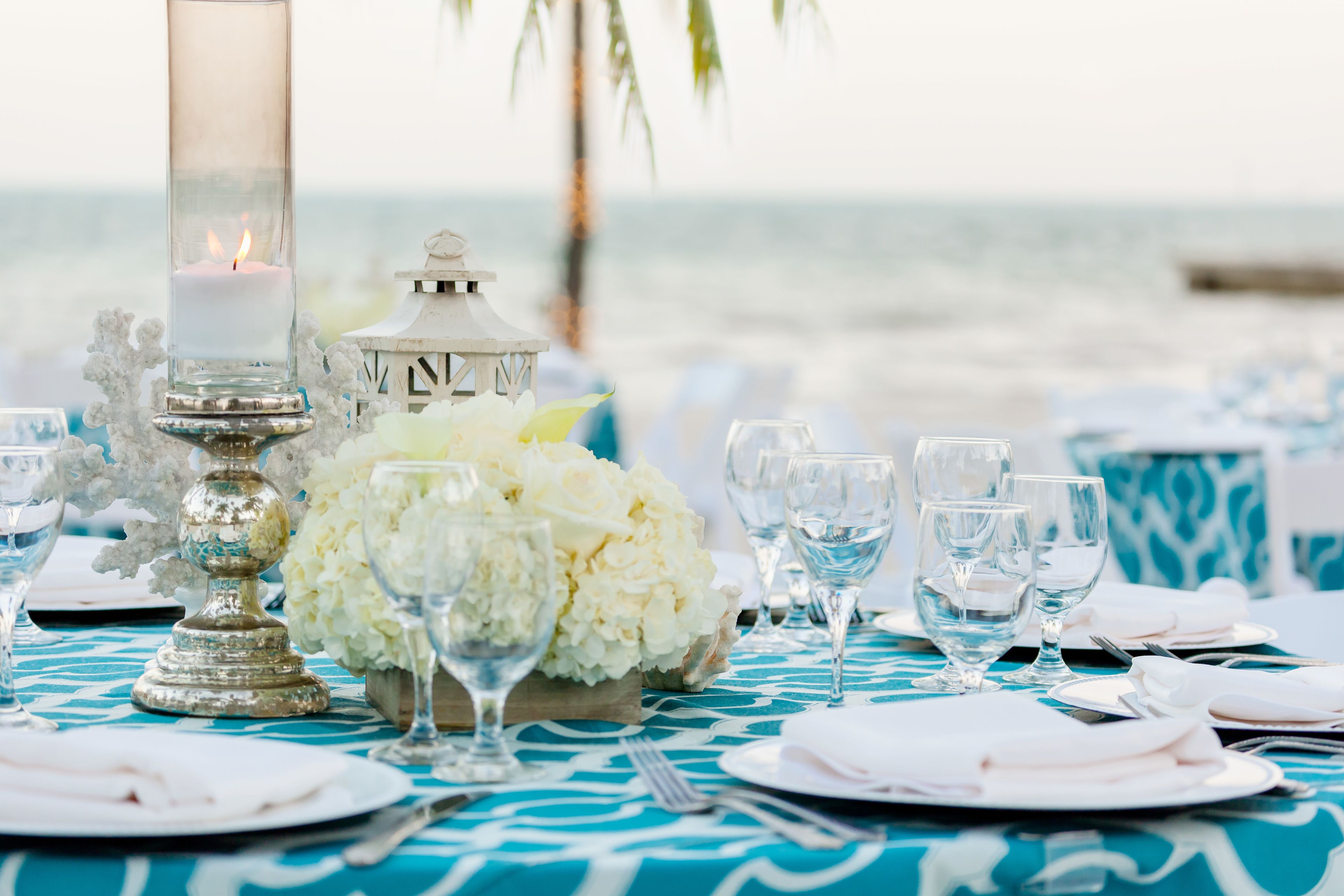 A table set for a meal with a candle, white flowers, and clear glasses.