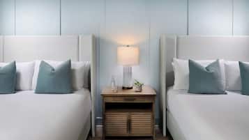 A hotel room with two beds, a nightstand with a lamp, and a small cabinet.