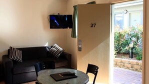 A room with a sofa, a table, and a TV mounted on the wall. - Travellers Motor Village (Mayfield West)