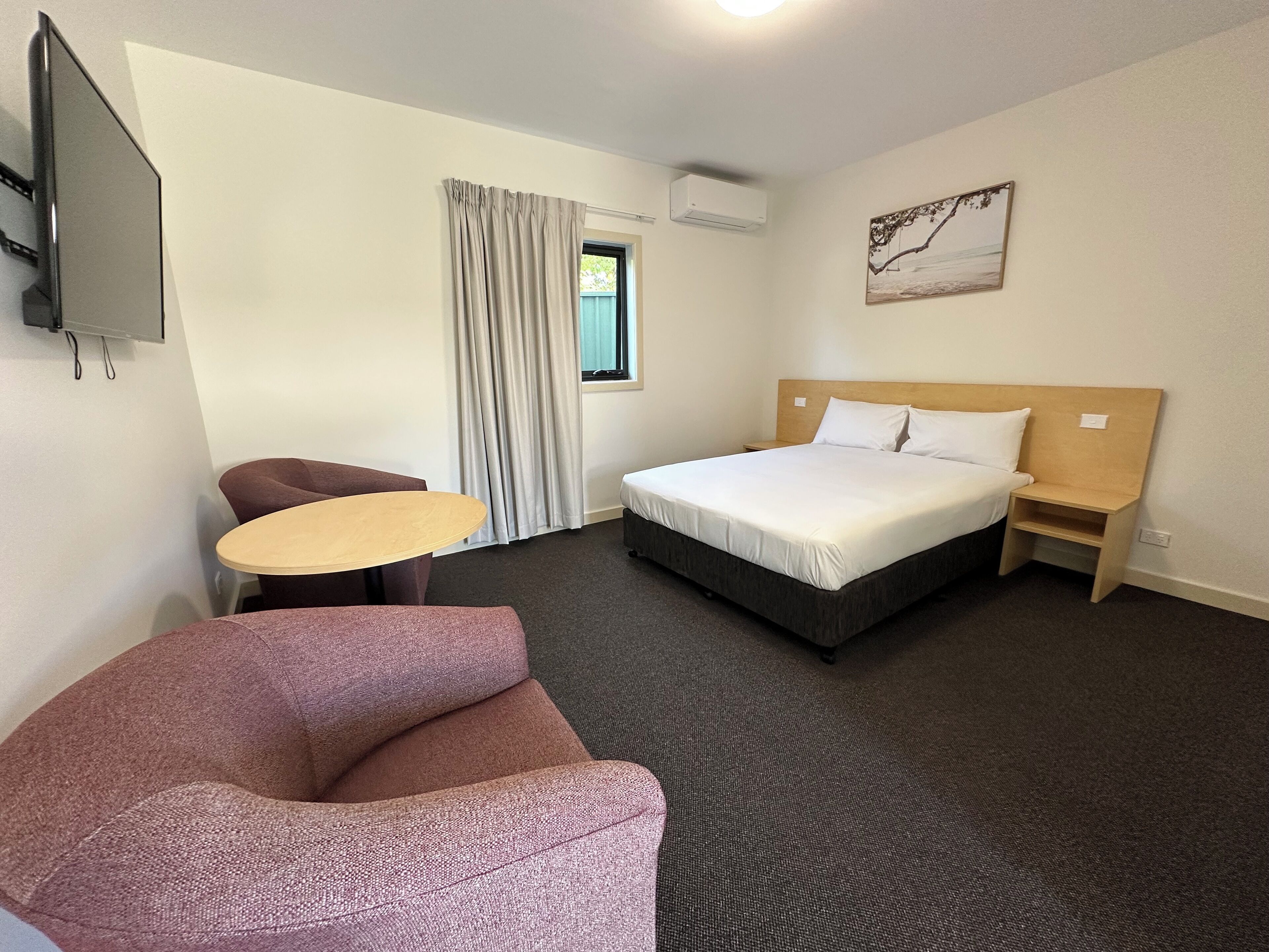 Una camera d'albergo con un letto, una scrivania, una sedia e una televisione.