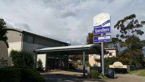 Señal de Travellers Motor Village con servicios como Wi-Fi gratuito, estacionamiento gratis y una recepción.