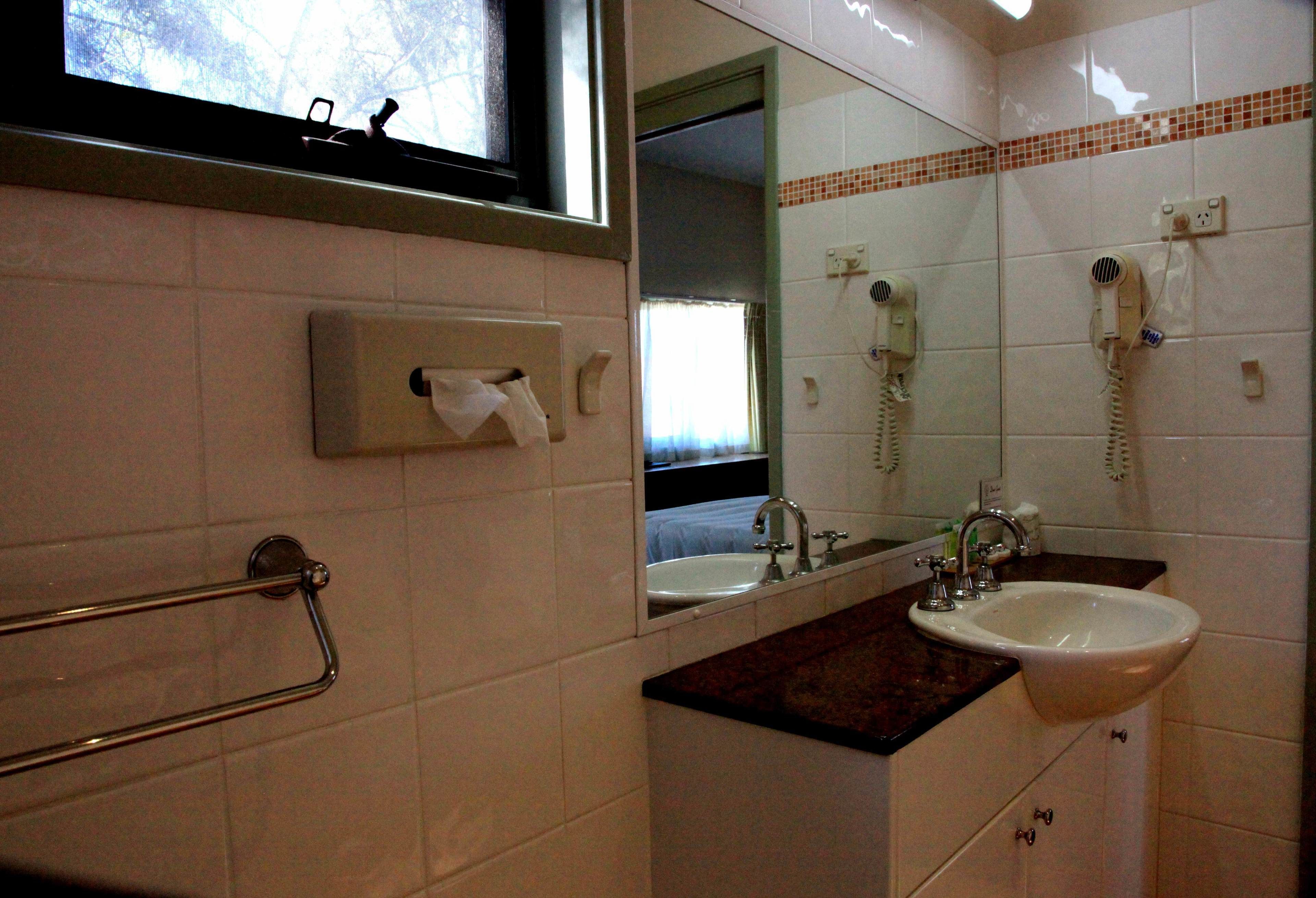 Un baño con lavamanos, espejo, toallero y dos teléfonos.