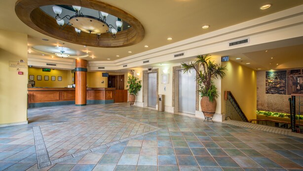 A spacious lobby with a reception desk, multiple elevators, and a large central column. - Mary's Well Nazareth By Dan Hotels (Nazareth)