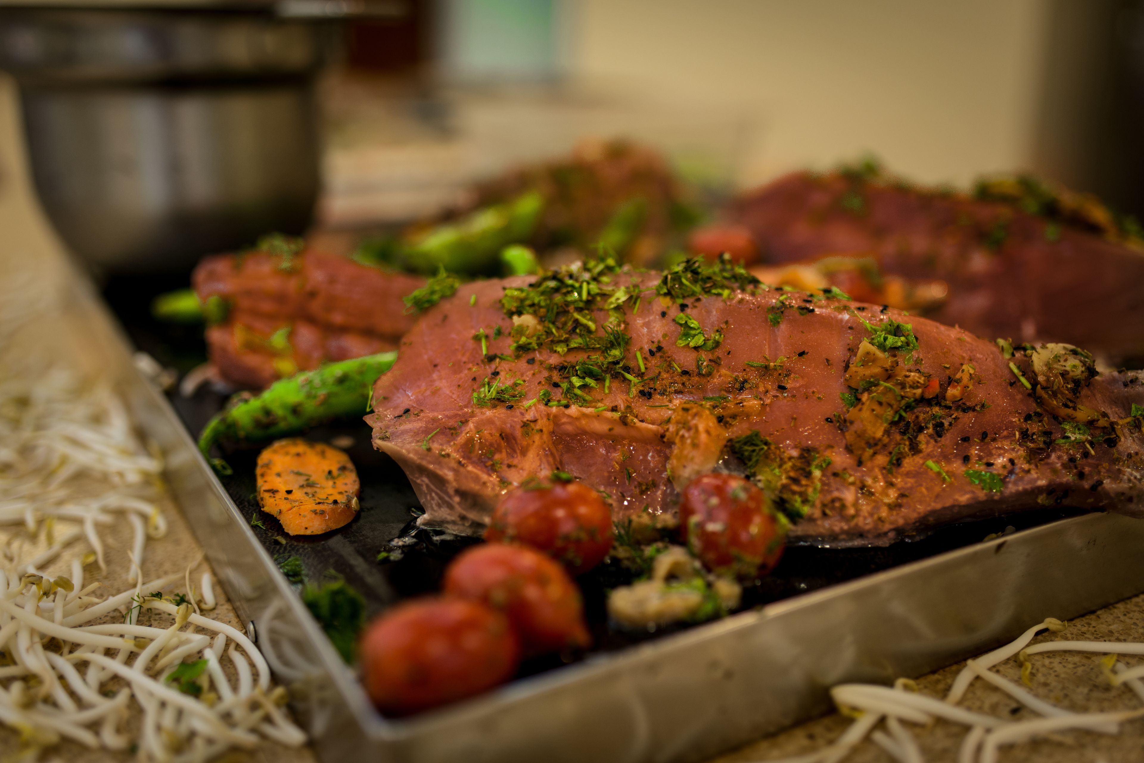 Un plateau contenant de la viande rôtie, des légumes et des herbes aromatiques.
