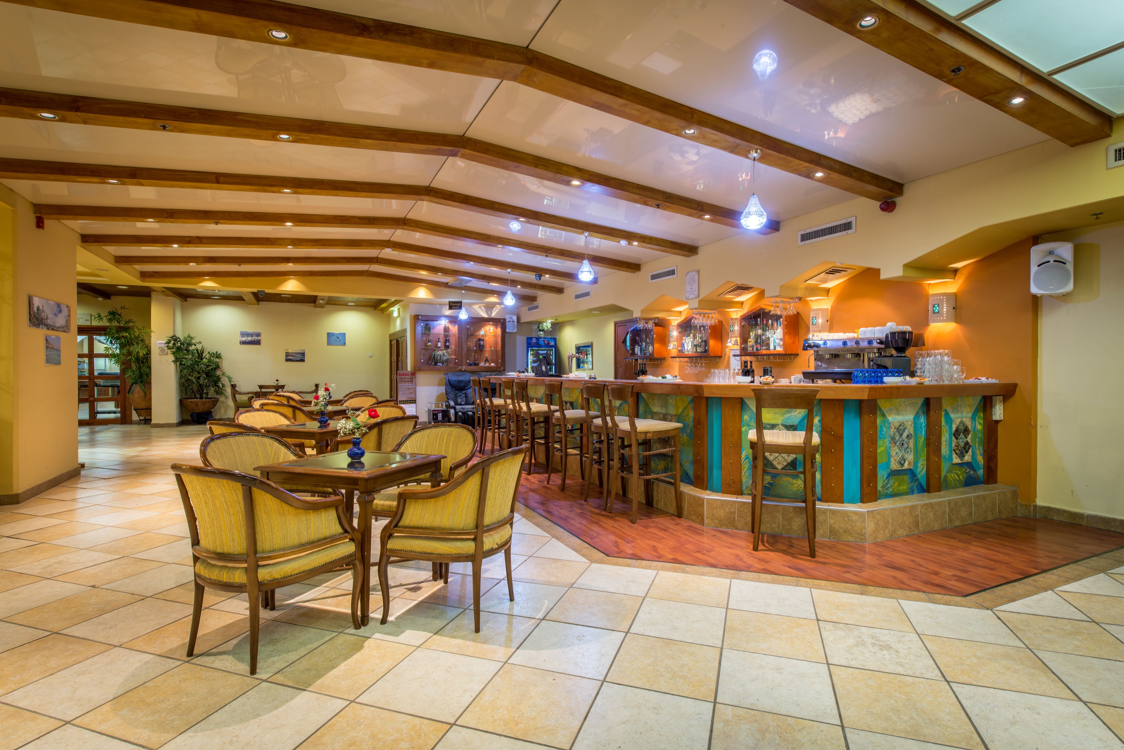A restaurant with wooden furniture, a bar area, and tiled flooring.